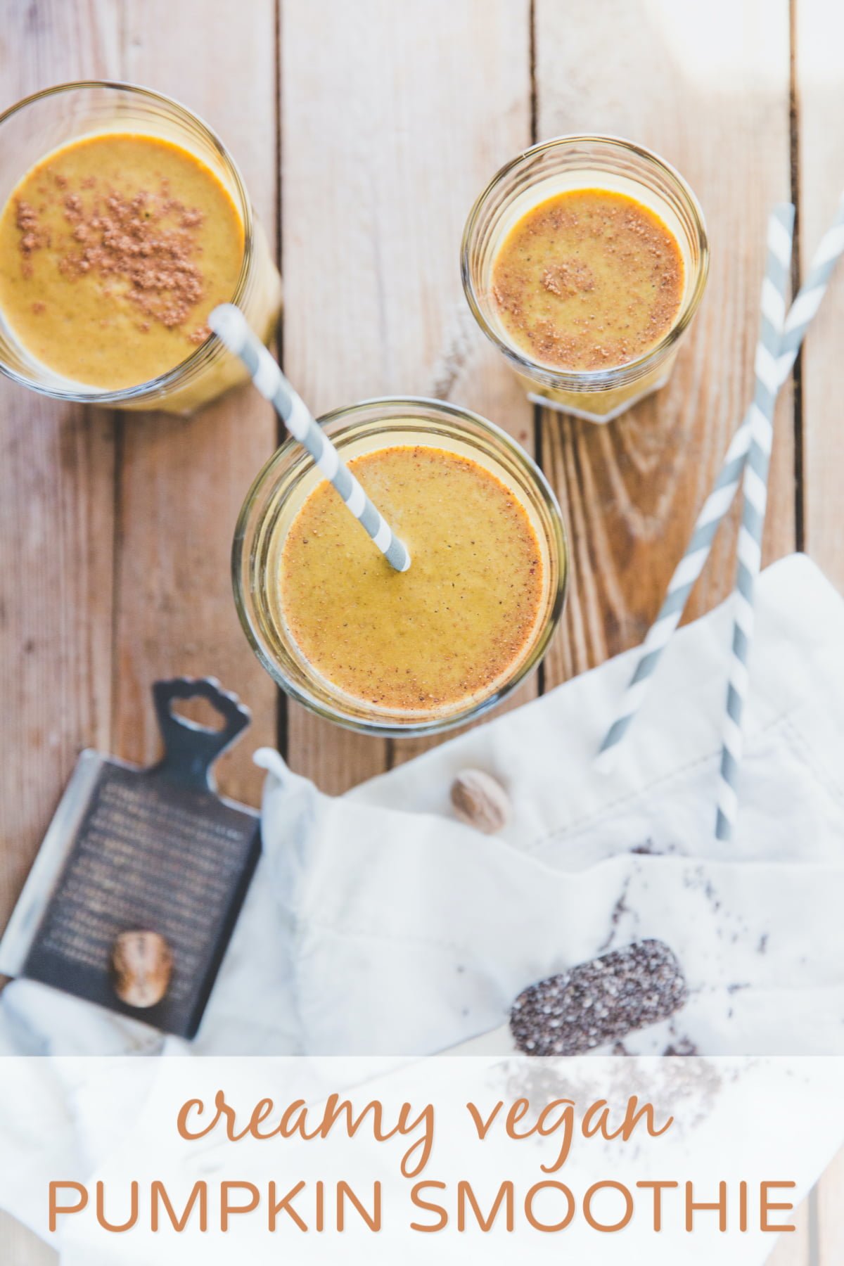 Three glasses of vegan pumpkin smoothies with striped paper straws