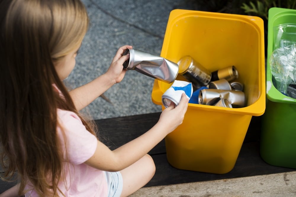 Earth-conscious kids - child separating items into recycling bins