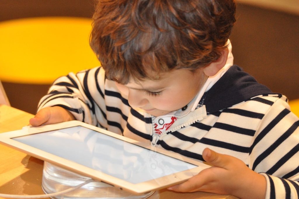 Child holding ipad up close, dangers of EMF exposure to kids