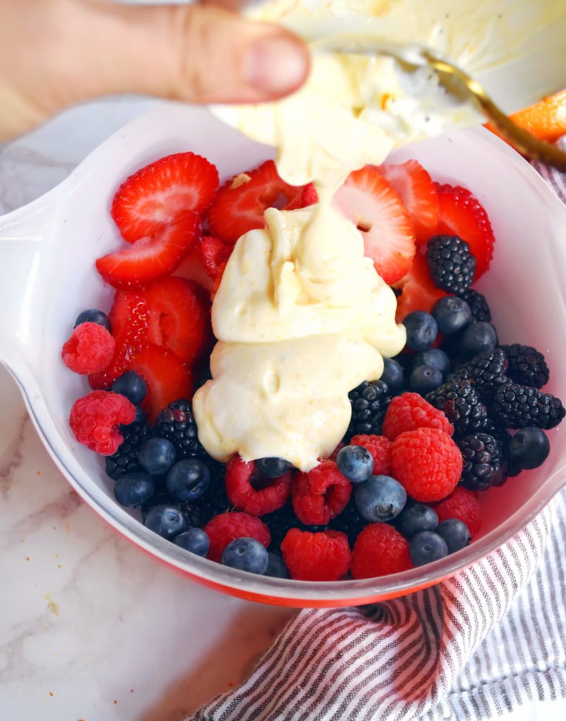 Bowl of fresh berries spooning yogurt on top