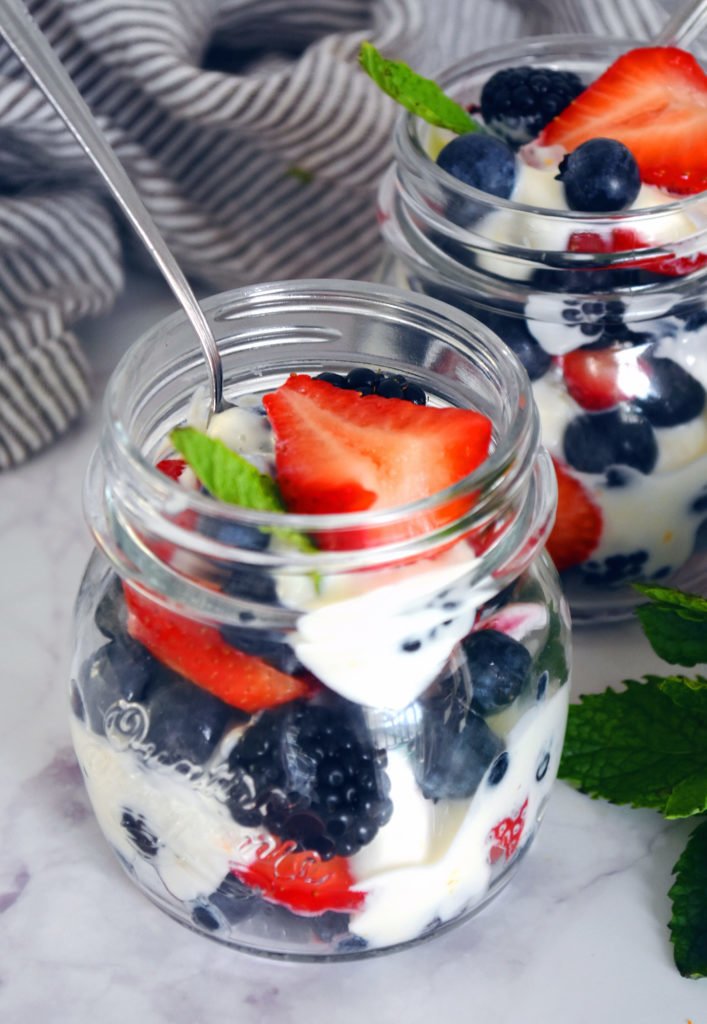 Layered berry fruit salad with Greek yogurt in mason jars