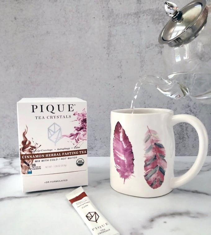 Pique Cinnamon Herbal Fasting Tea packets and mug of Pique tea crystals filled with tea kettle