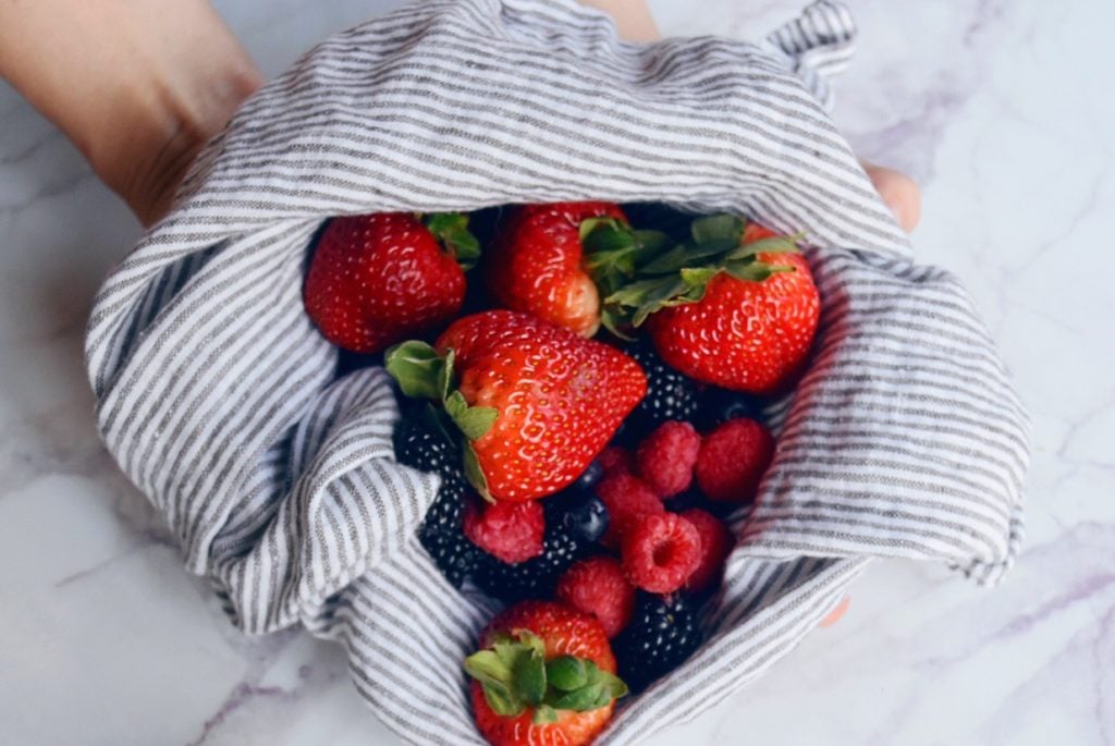 Fresh summer berries in dish towel on white marble countertop