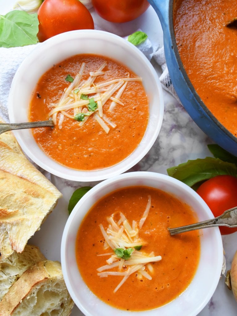 Roasted tomato basil soup in two bowls by dutch oven