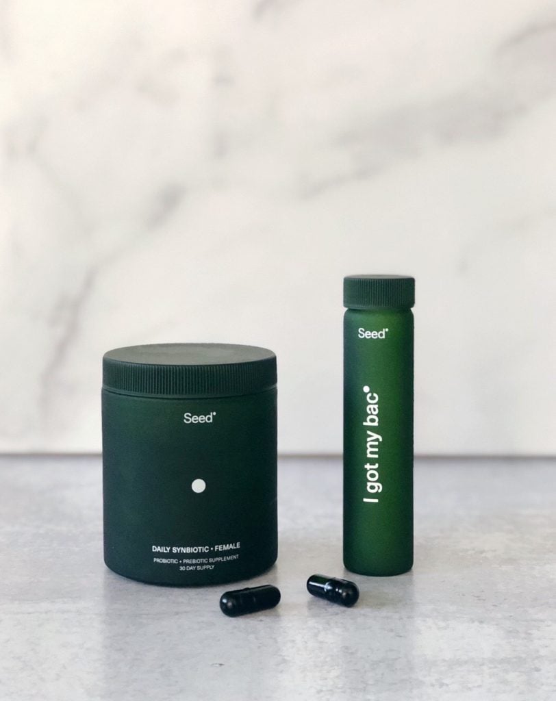 Seed daily synbiotic bottle and travel vial on concrete countertop