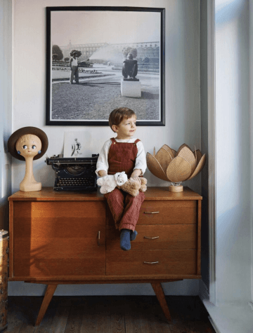 Child sitting on midcentury modern dresser looking out window