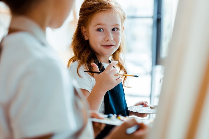 Creative child - girl painting and easel