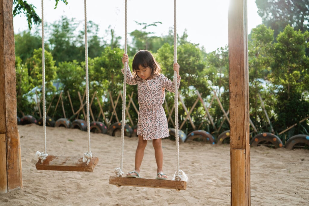 girl on wooden swing outside balancing nervous system