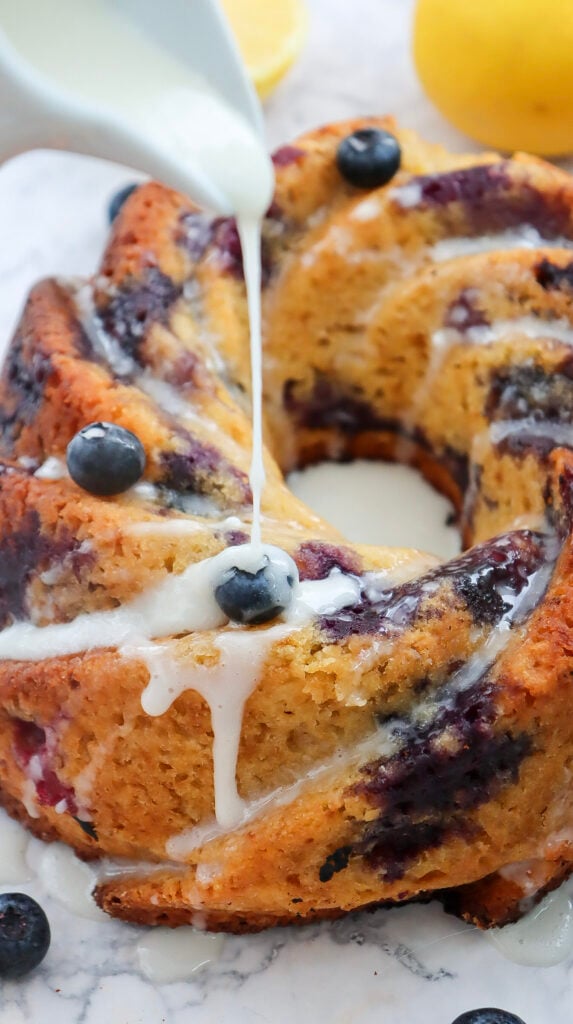 drizzling glaze on blueberry cake